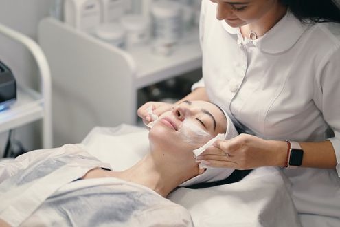 Person receiving facial treatment from a professional in a spa setting.