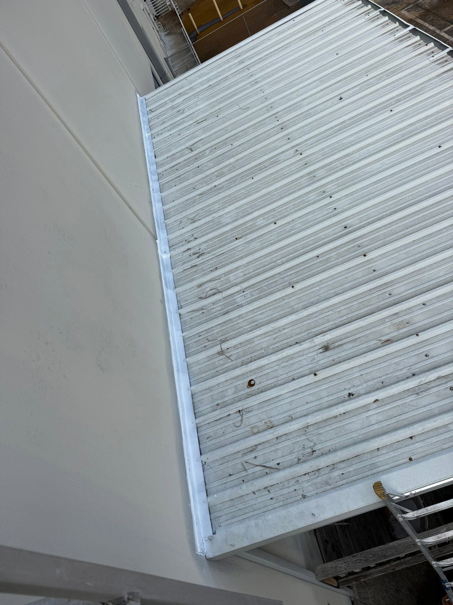 White corrugated metal ramp or walkway beside a light gray wall, viewed at an angle