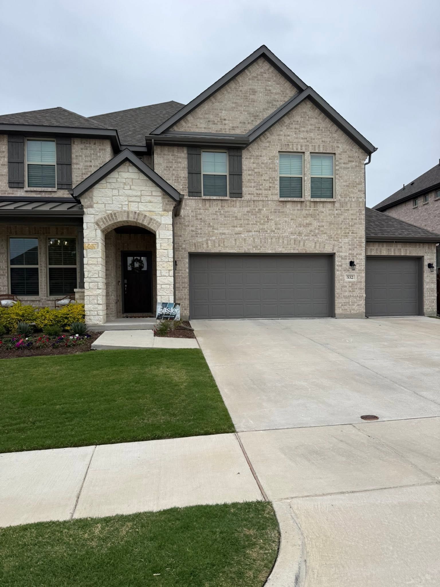 Suburban two-story brick house with a double garage and concrete driveway