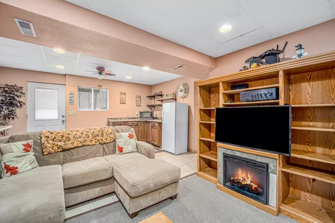 Cozy living room with beige sectional, wooden TV wall, fireplace, and light peach walls