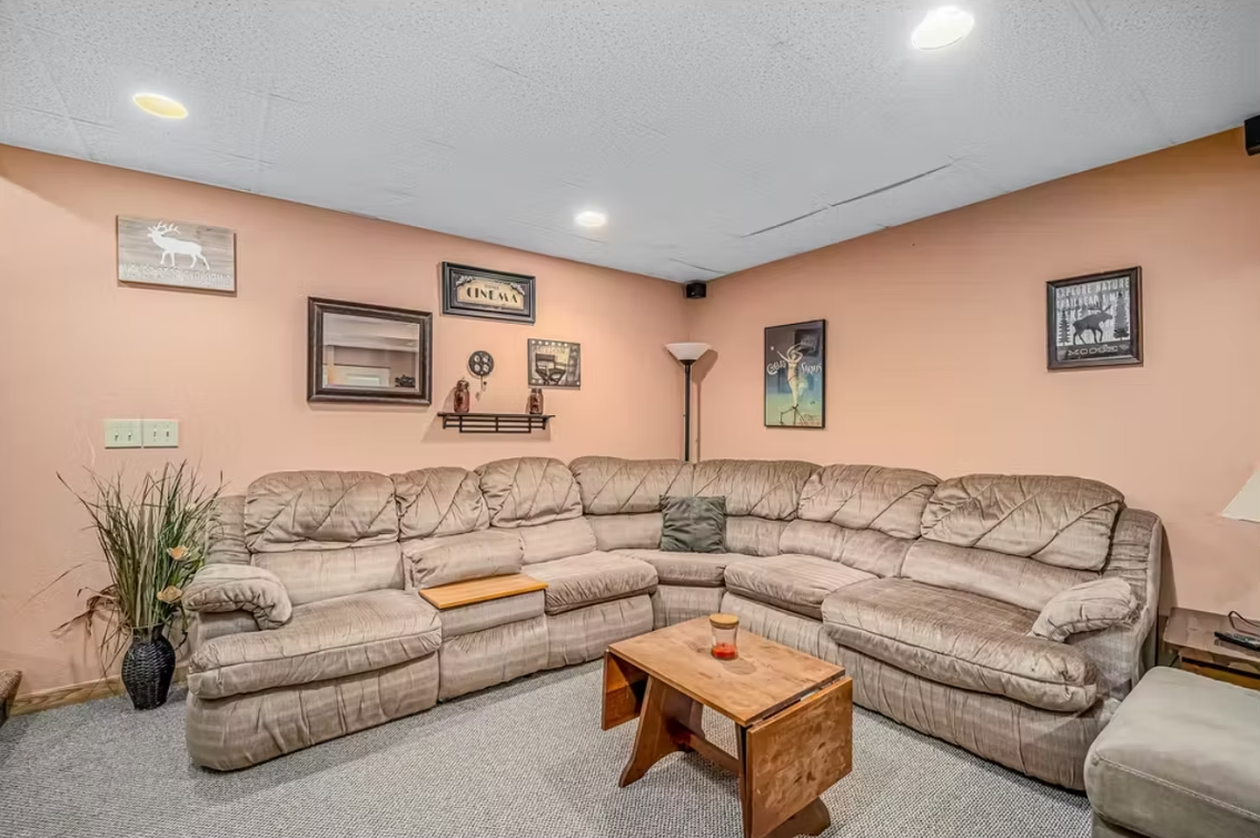 Beige sectional sofa in a cozy living room with peach walls, framed art, lamp, and small coffee table
