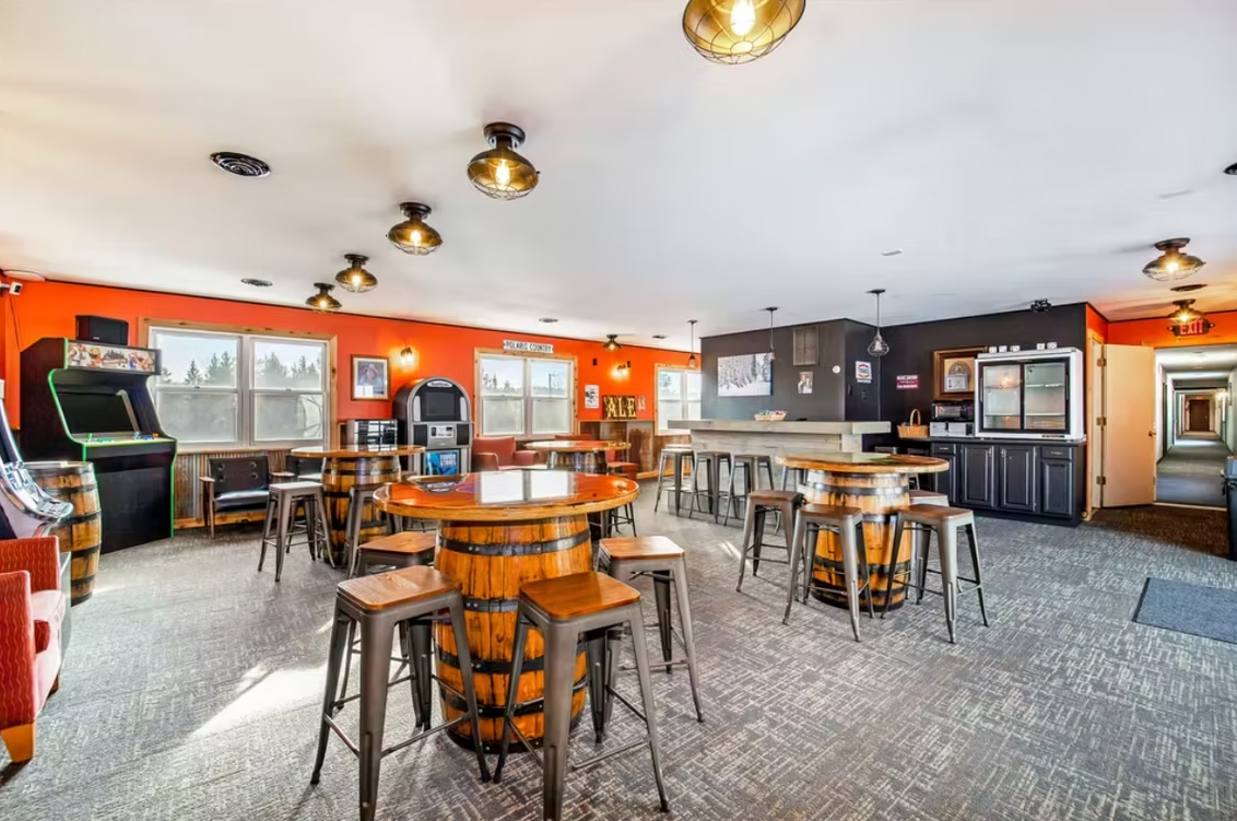 Bright orange casual dining room with tables, stools, booths, and a bar counter