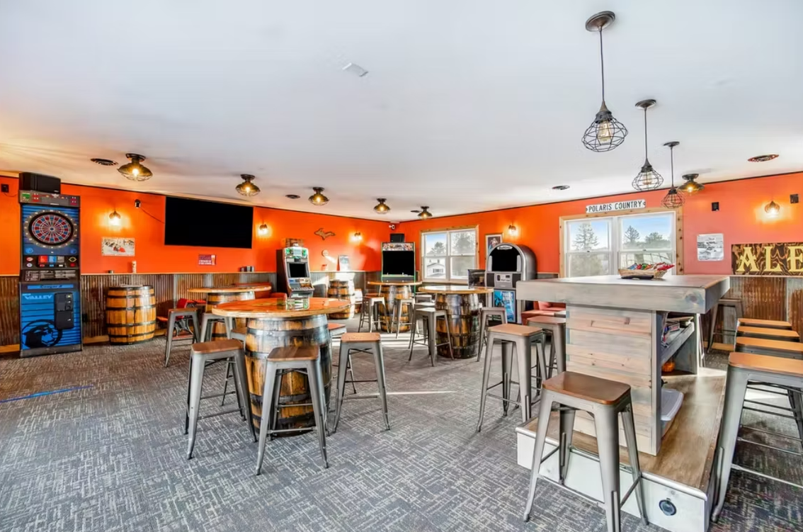 Bright orange café interior with metal tables, stools, and a counter under hanging lights