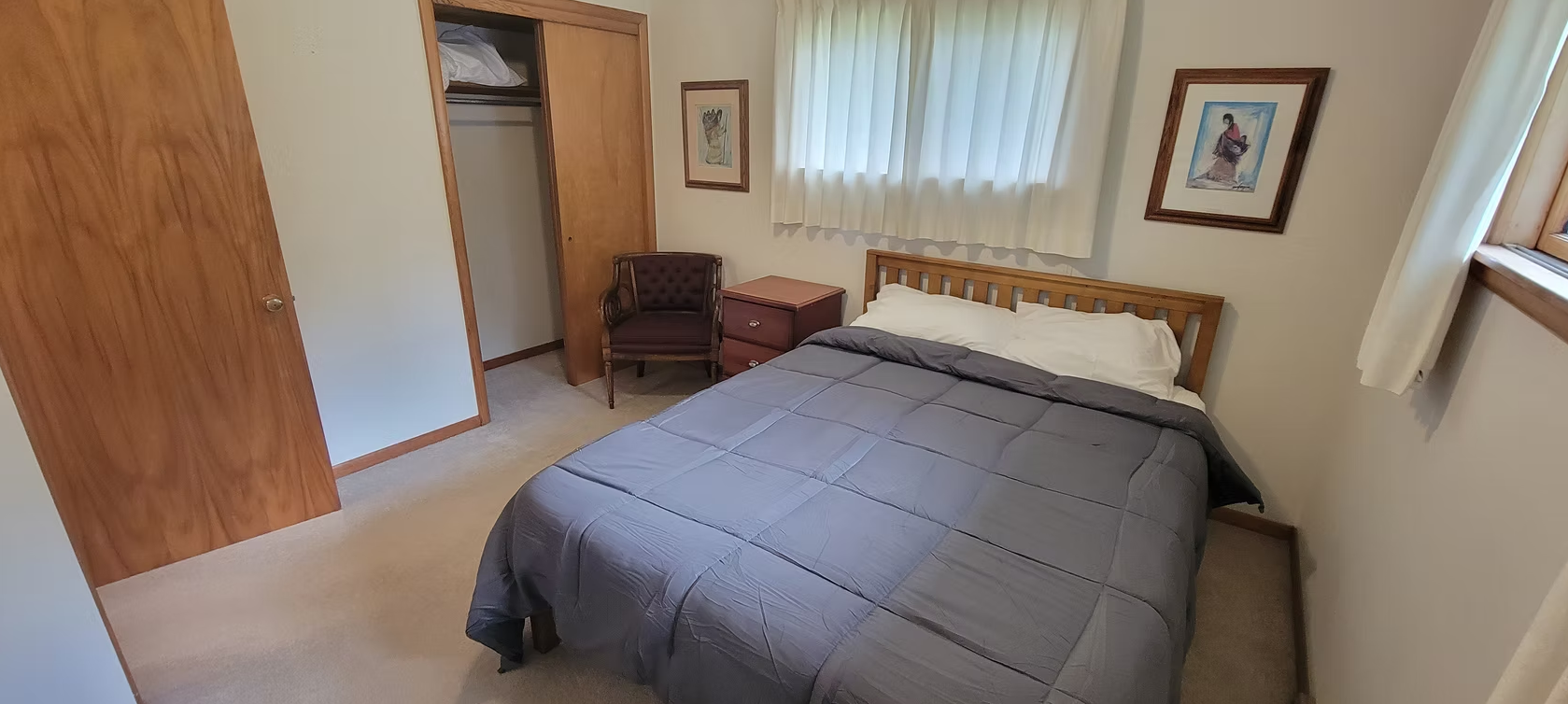 Bedroom with a bed, wooden dresser, window curtains, and framed wall art