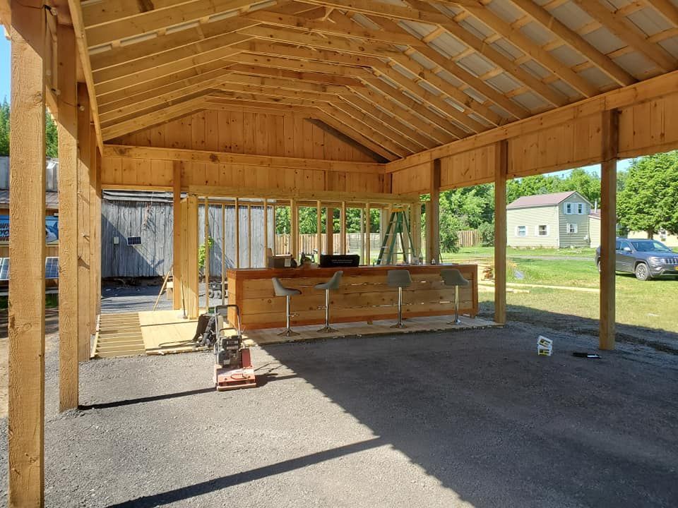 A wooden structure with an outdoor bar under construction on a paved surface.