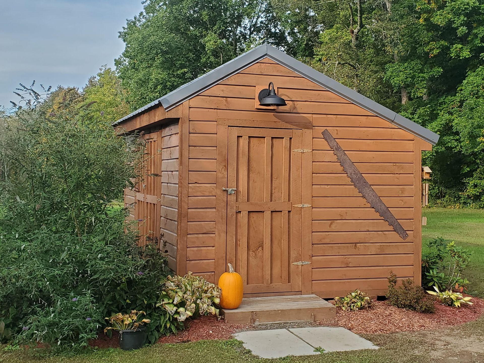 Brown wooden shed with a pumpkin, in a garden.
