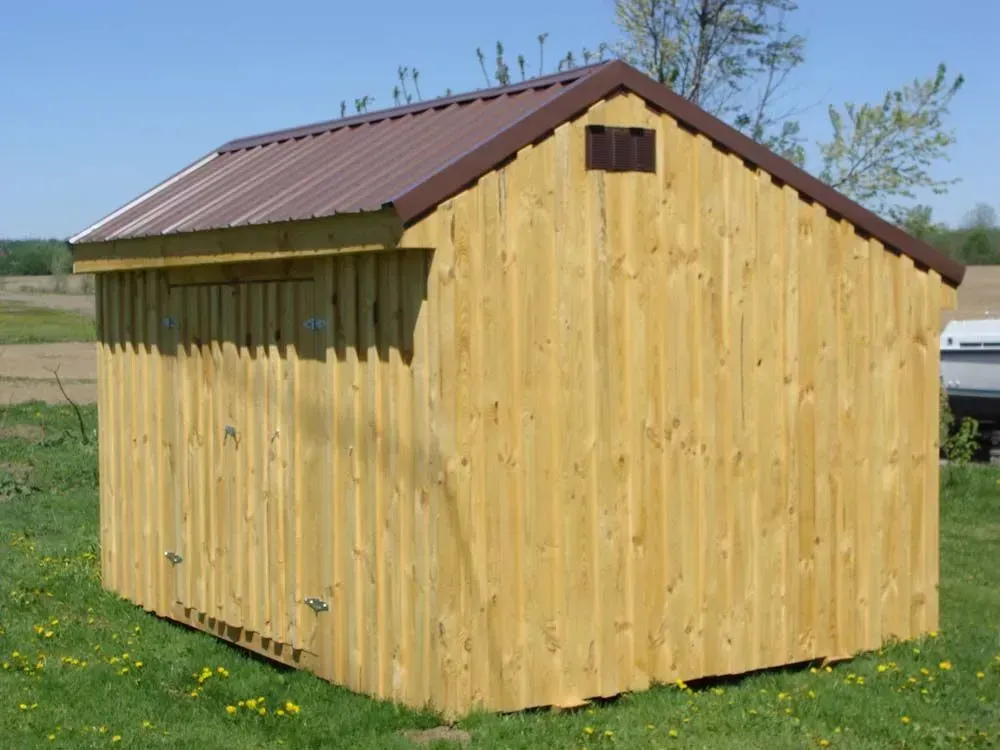 Wooden shed with brown metal roof in a grassy field.