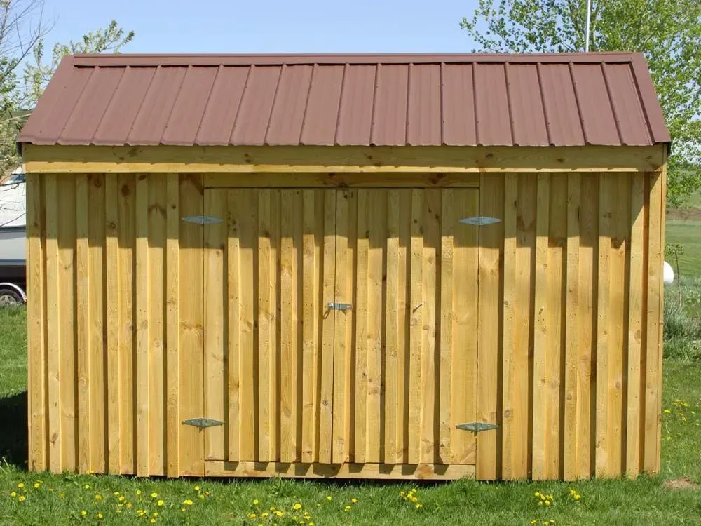 Wooden shed with brown metal roof, green grass, and two hinged doors.