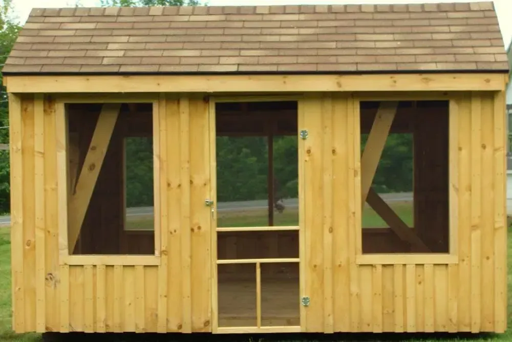 Wooden shed with screen door and windows, set on green grass, brown roof.