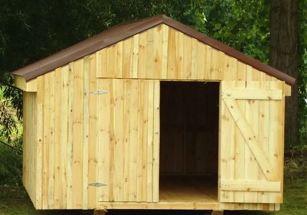 Wooden shed with brown metal roof and open doorway, outdoors.