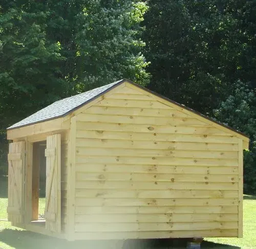 Wooden shed with open doors and green roof, set outdoors.