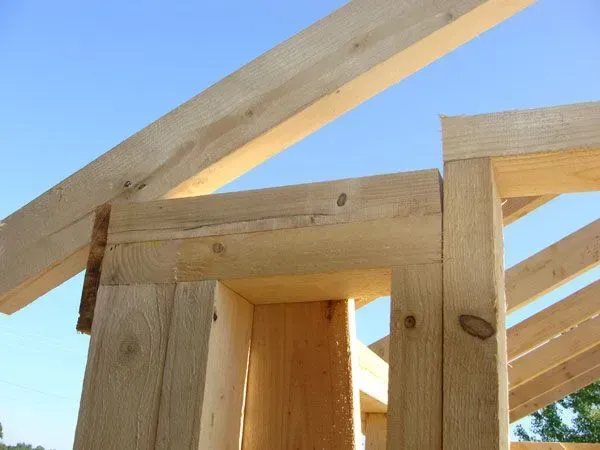 Wooden frame of a building under construction; blue sky in background.