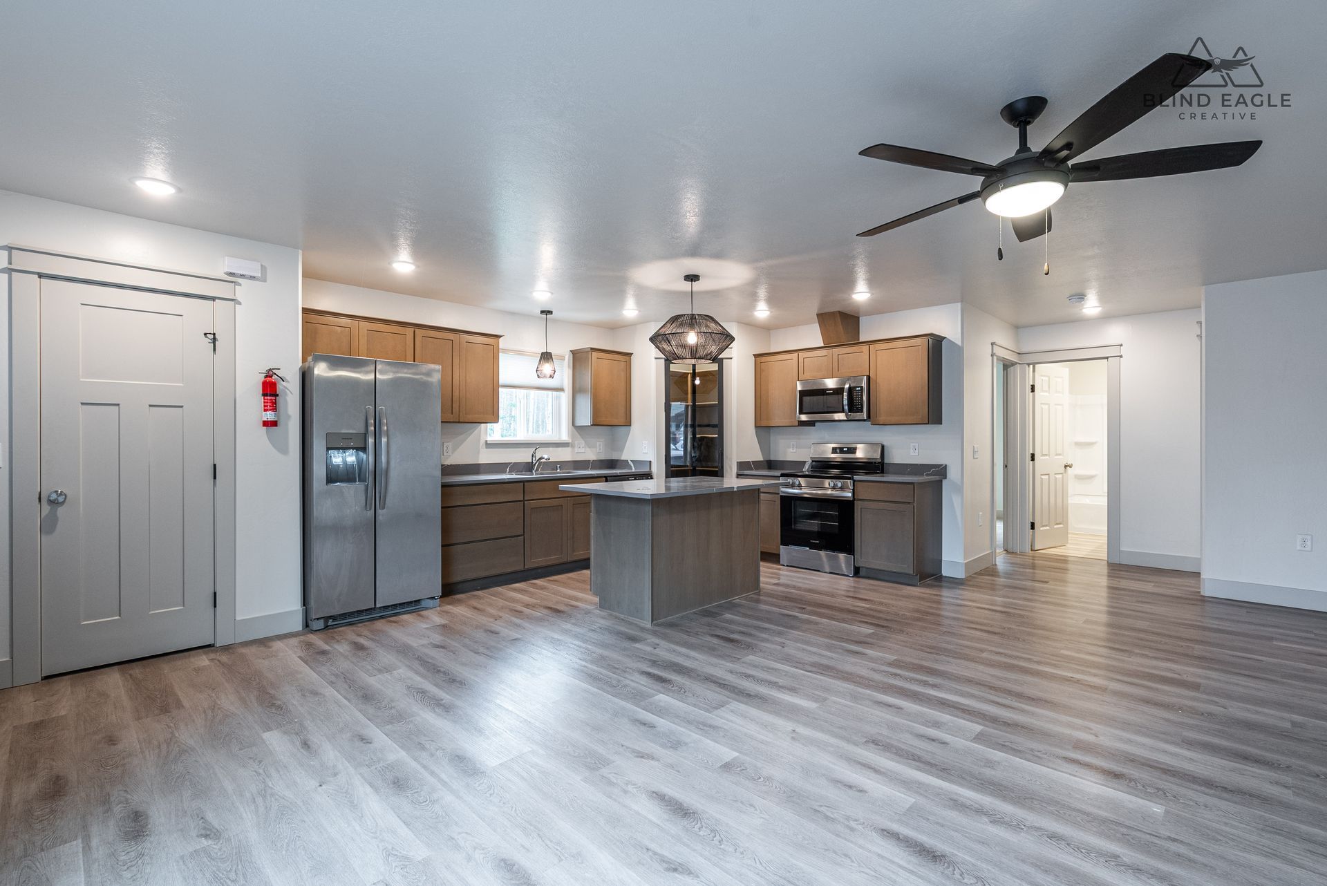 Modern open-concept kitchen with light gray flooring, stainless steel appliances, and a central island.