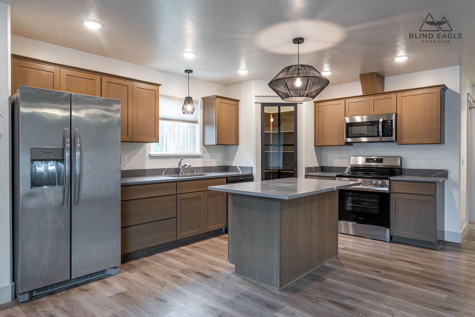 Modern kitchen with stainless appliances, wood cabinets, island, and pendant lights