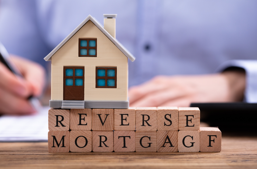 A house is sitting on top of wooden blocks that say reverse mortgage.