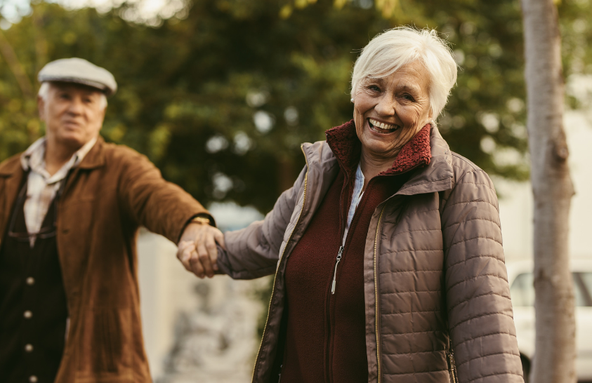 An elderly couple is shaking hands while walking down the street.