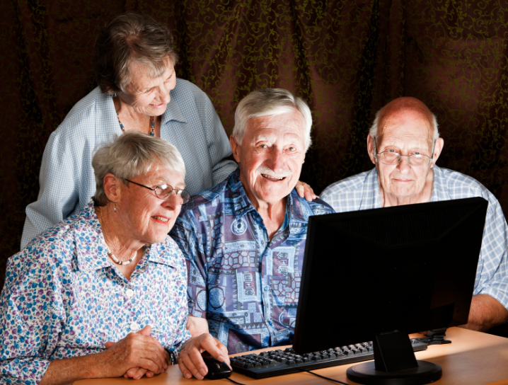 A group of elderly people are looking at a computer screen.