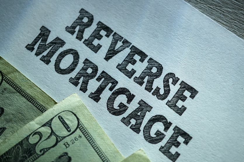 A 20 dollar bill is laying on top of a piece of paper that says reverse mortgage.