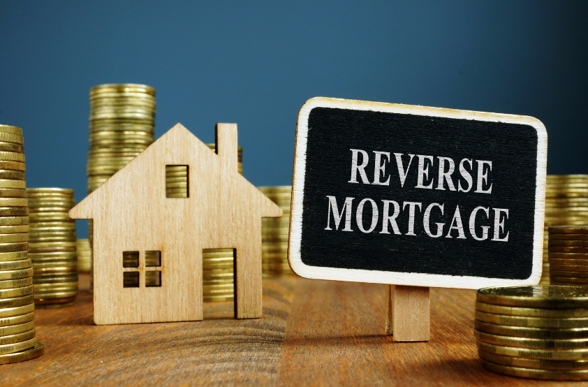 A wooden house is sitting next to a sign that says reverse mortgage.