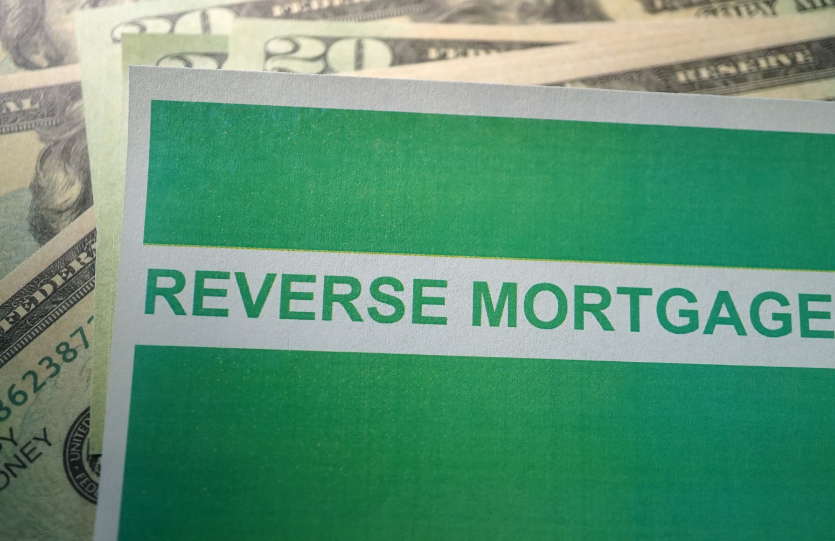 A green sign that says reverse mortgage is sitting on top of a pile of money.