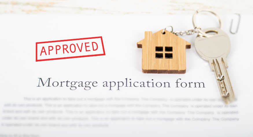 A mortgage application form with a key and a house keychain on it.