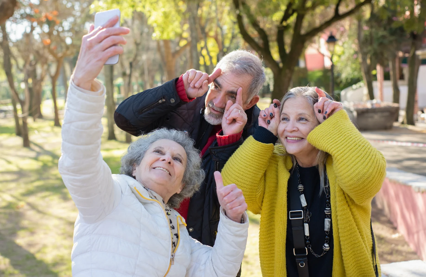 A group of elderly people are taking a selfie in a park.