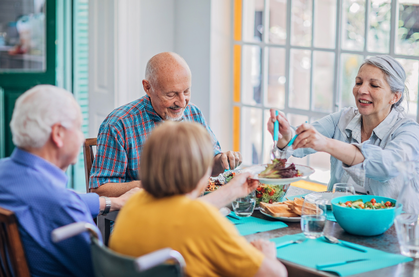 A group of elderly people are sitting at a table eating food.