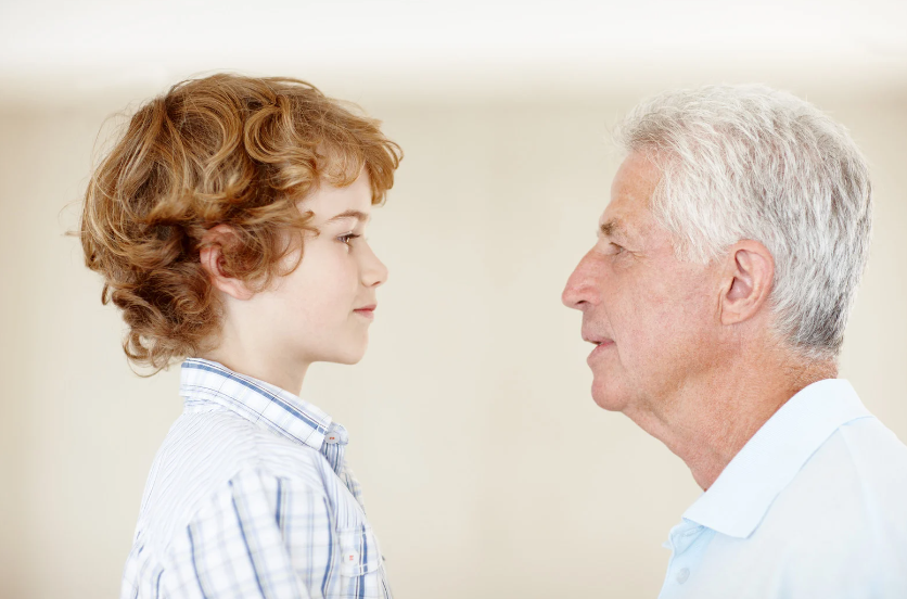 An older man and a young boy are looking at each other.