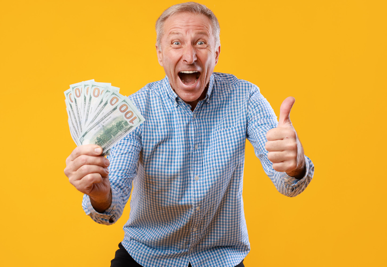 A man is holding a bunch of money and giving a thumbs up.