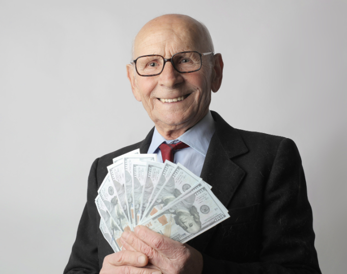 A man in a suit and tie is holding a fan of money.
