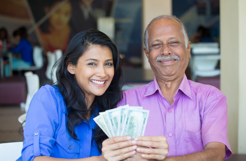 A man and a woman are sitting at a table holding money.