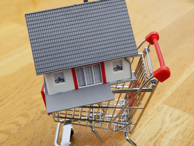 A shopping cart with a model house in it