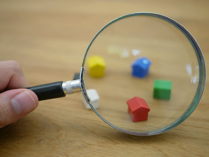 A person is holding a magnifying glass over a wooden table.