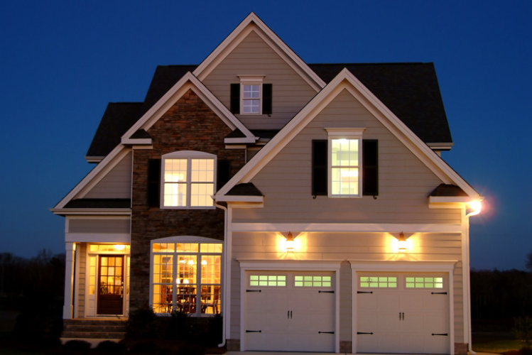 A house is lit up at night and has two garage doors