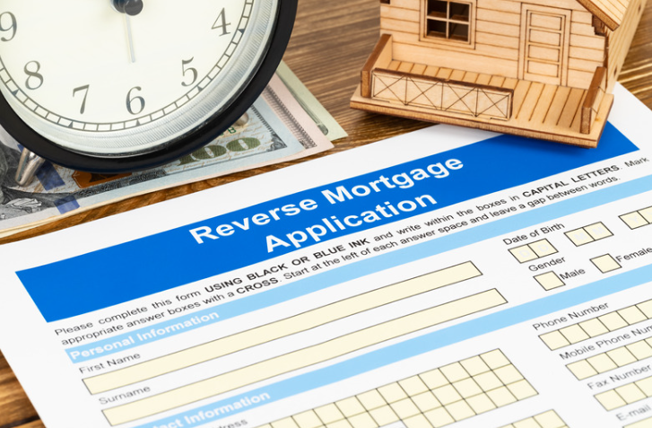 A reverse mortgage application is sitting on a table next to a clock and a model house.