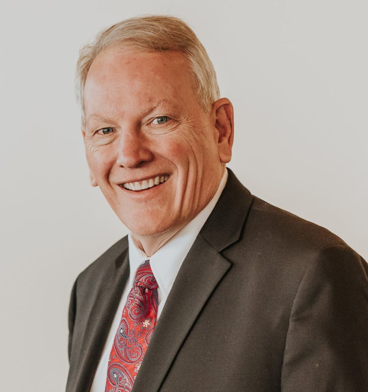 A man in a suit and tie is smiling for the camera