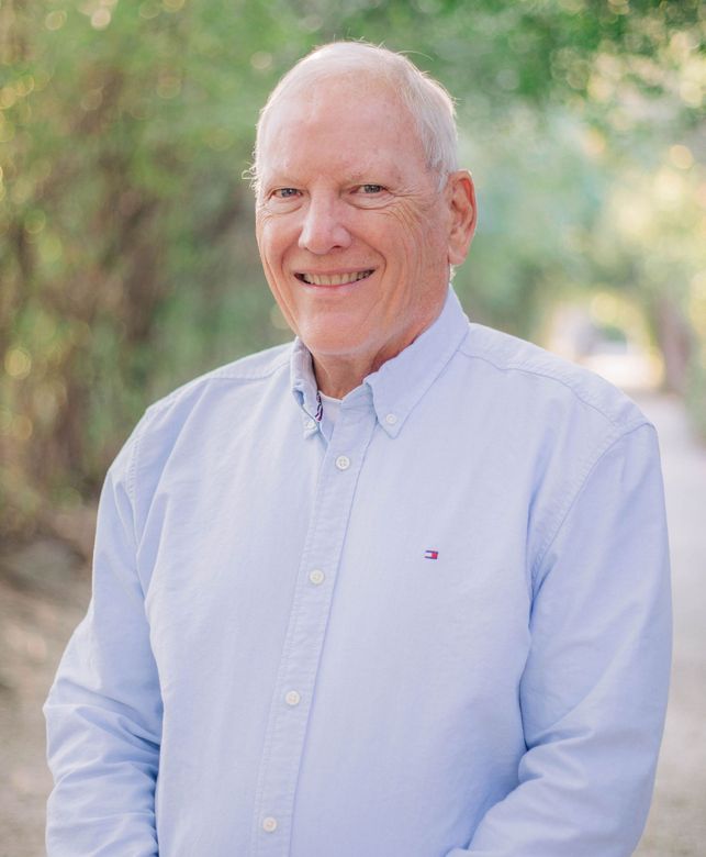 A man in a suit and tie is smiling for the camera