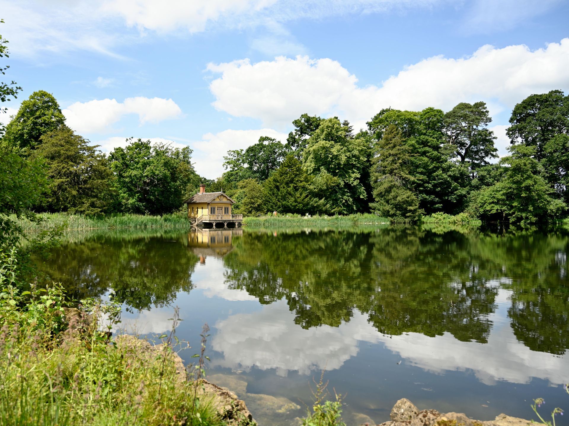 A small house sits on the shore of a lake surrounded by trees
