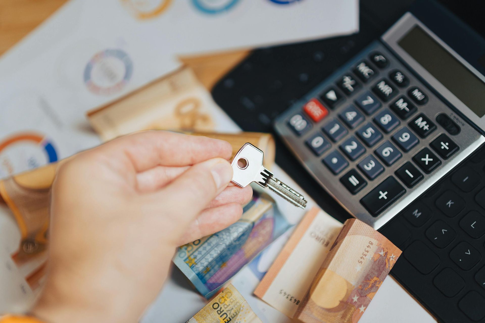 A person is holding a key in front of a calculator.