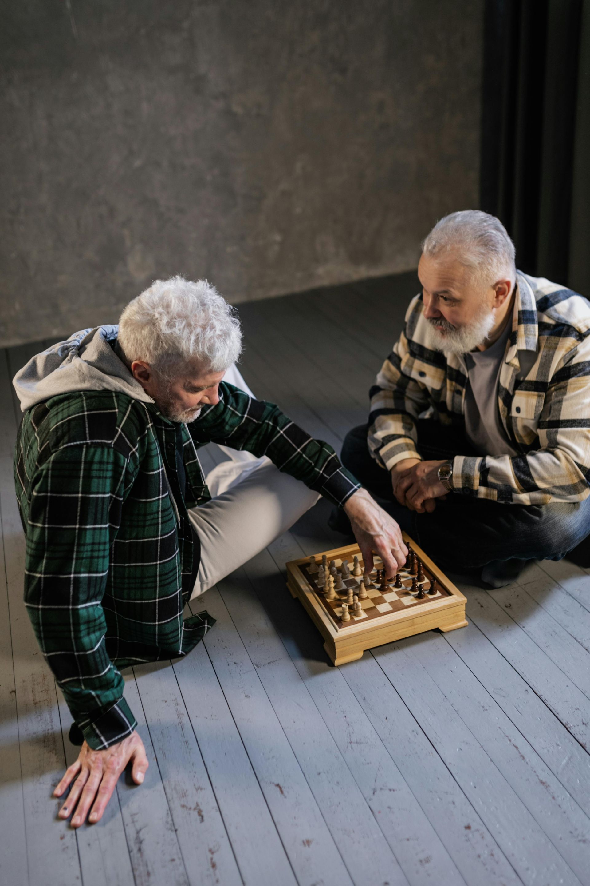Two men are sitting on the floor playing a game of chess.