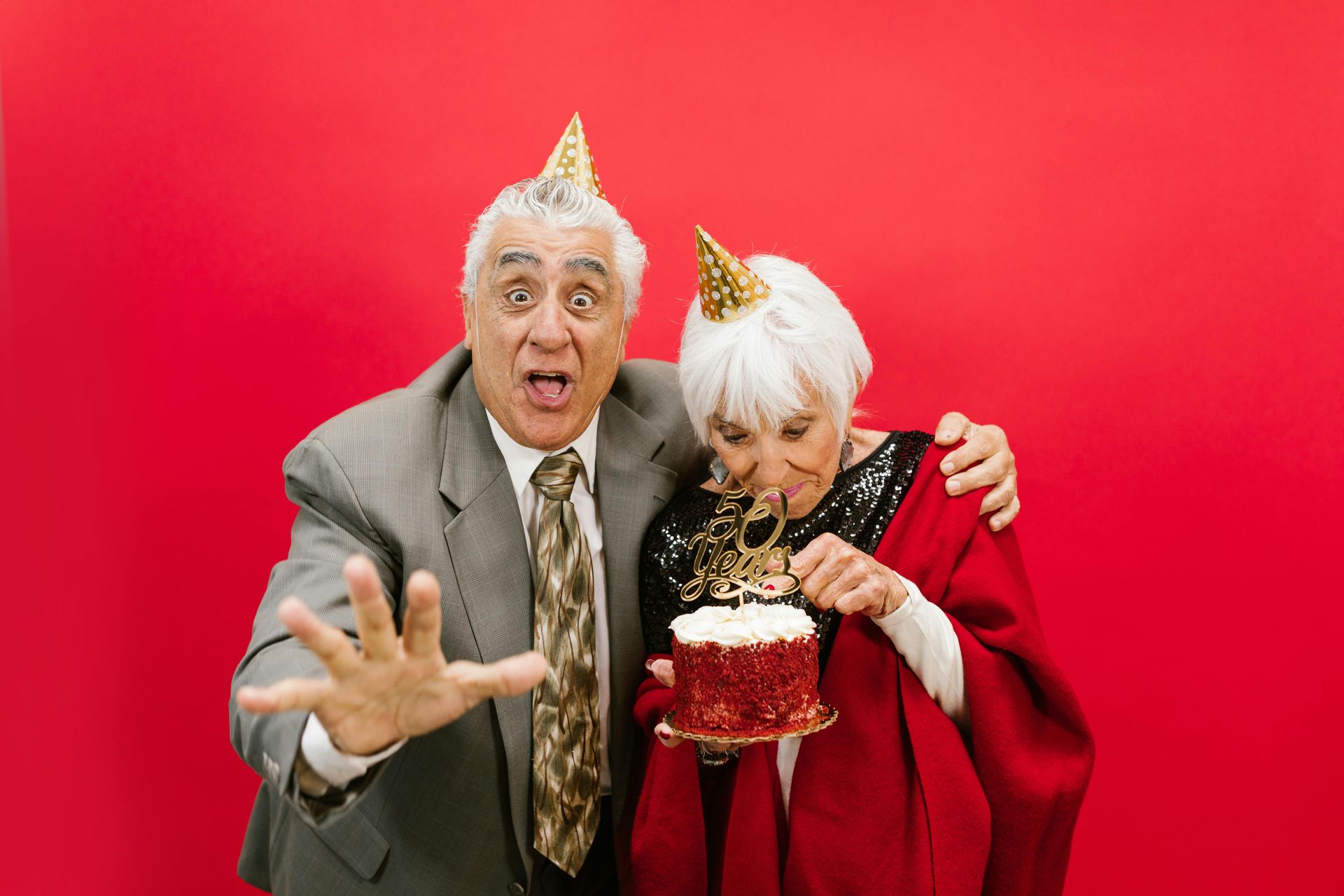 An elderly couple is celebrating a birthday with a cake.