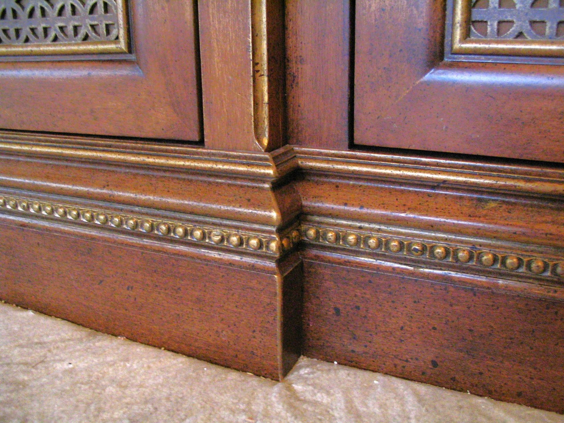 Close-up of a brown wooden cabinet with gold trim and textured details.