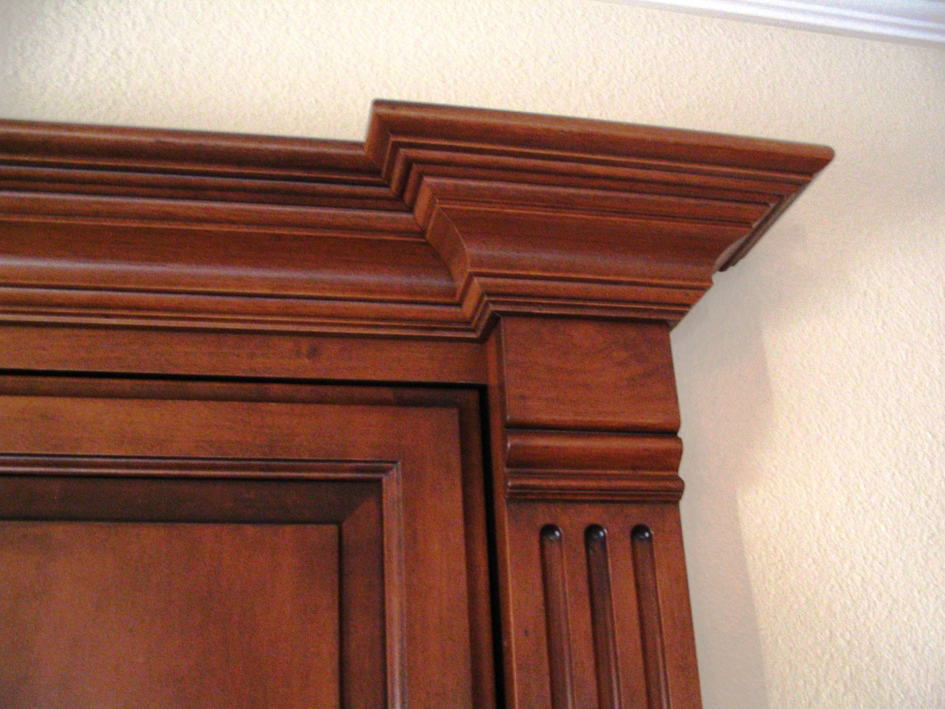 Wooden cabinet with ornate trim in a room with light-colored walls.