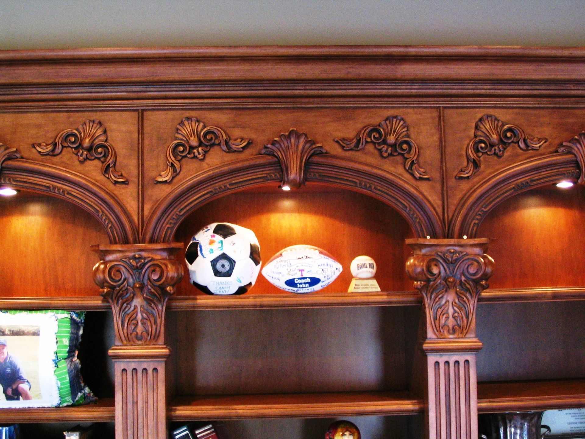 Wooden built-in shelving with sports balls displayed in arched niches.