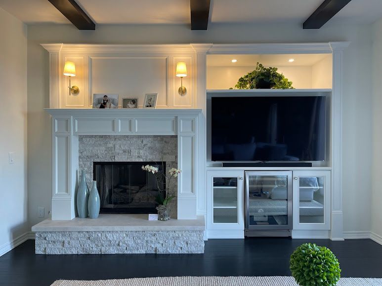 Fireplace with built-in entertainment center, white cabinetry, sconces, and a large TV. Dark wood floors.