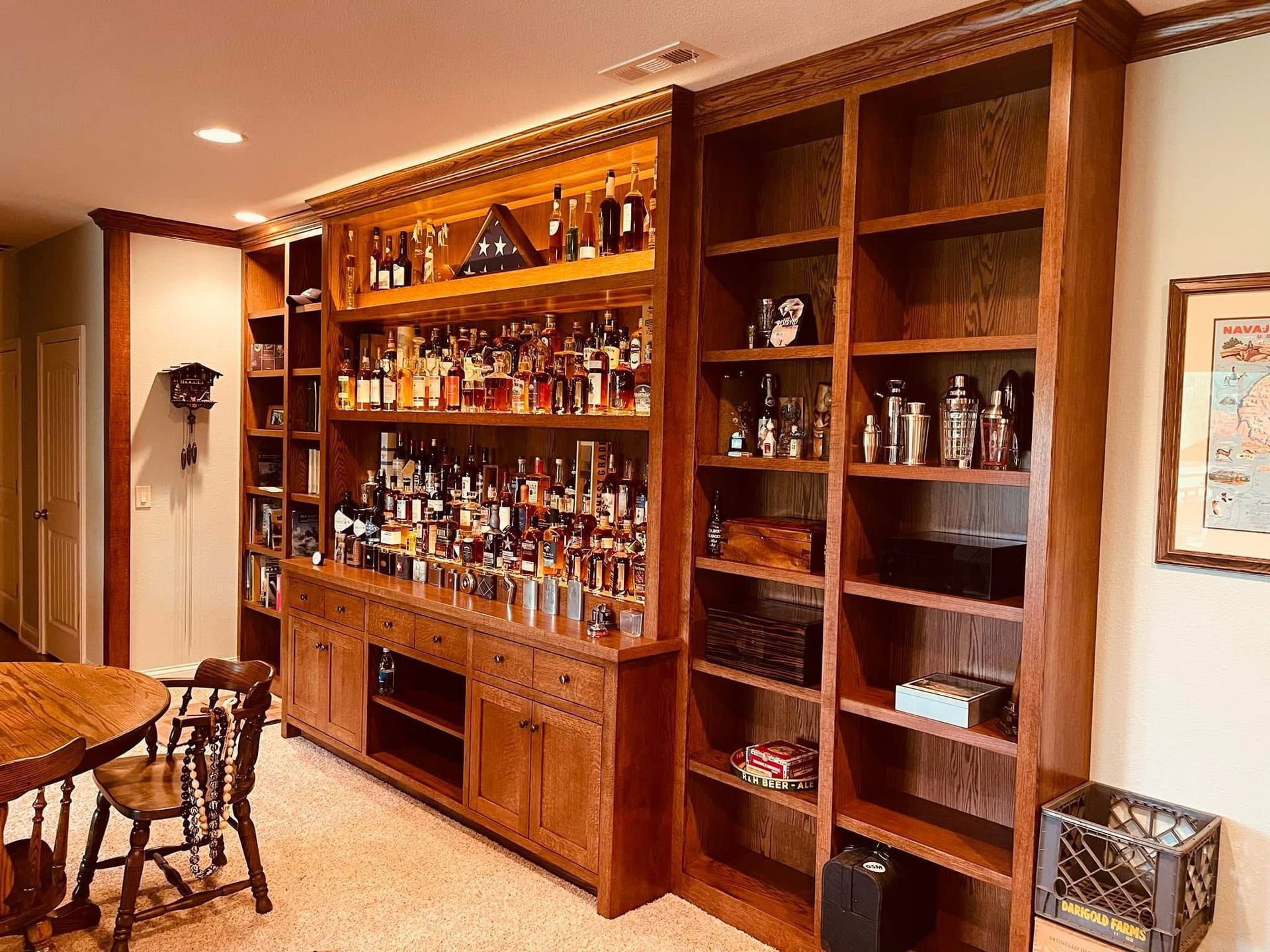Corner home bar with gray cabinets, mirrored backsplash, and shelves stocked with alcohol.