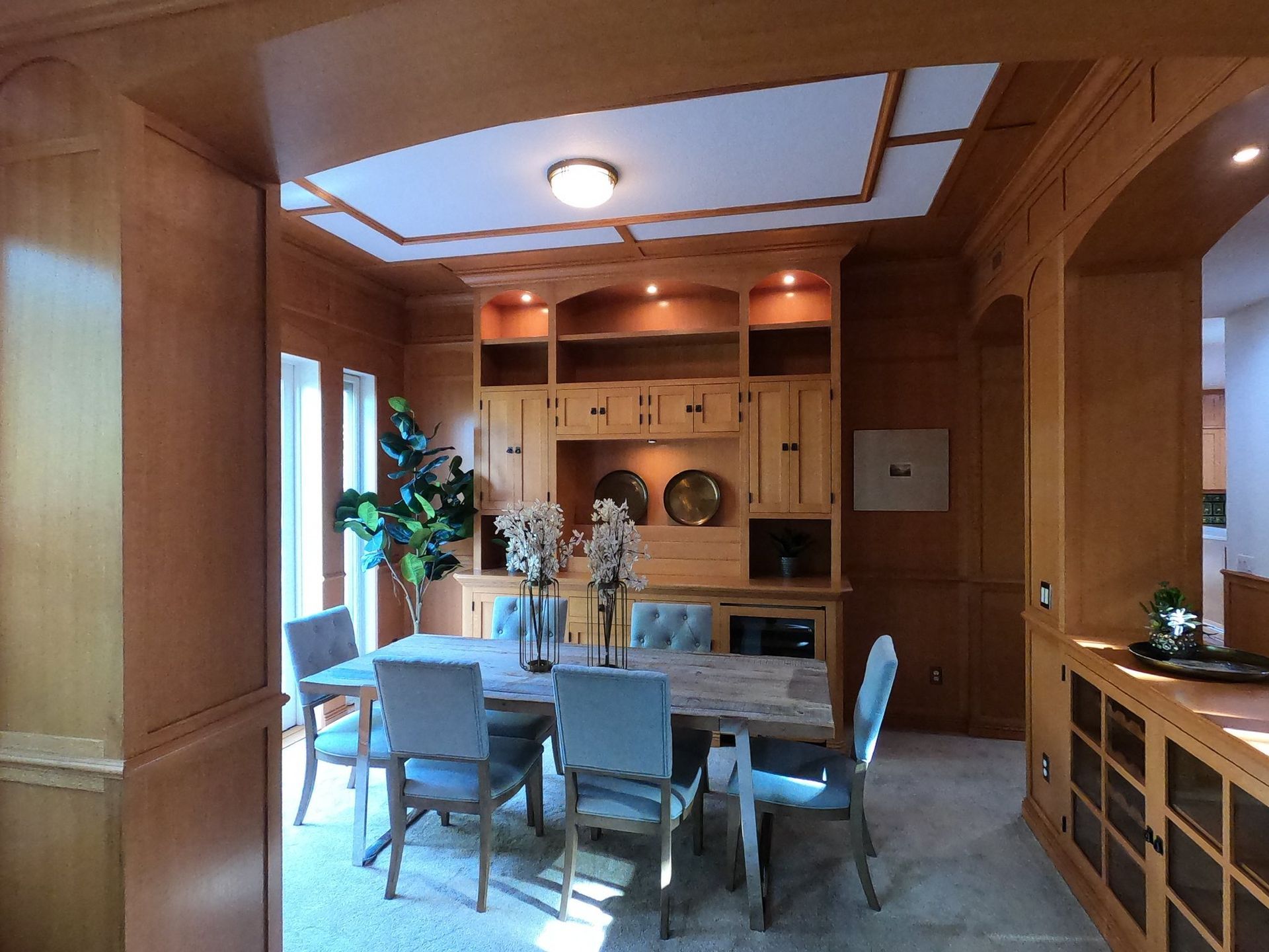 Dining room with wood paneling, built-in cabinet, dining table, and six chairs.
