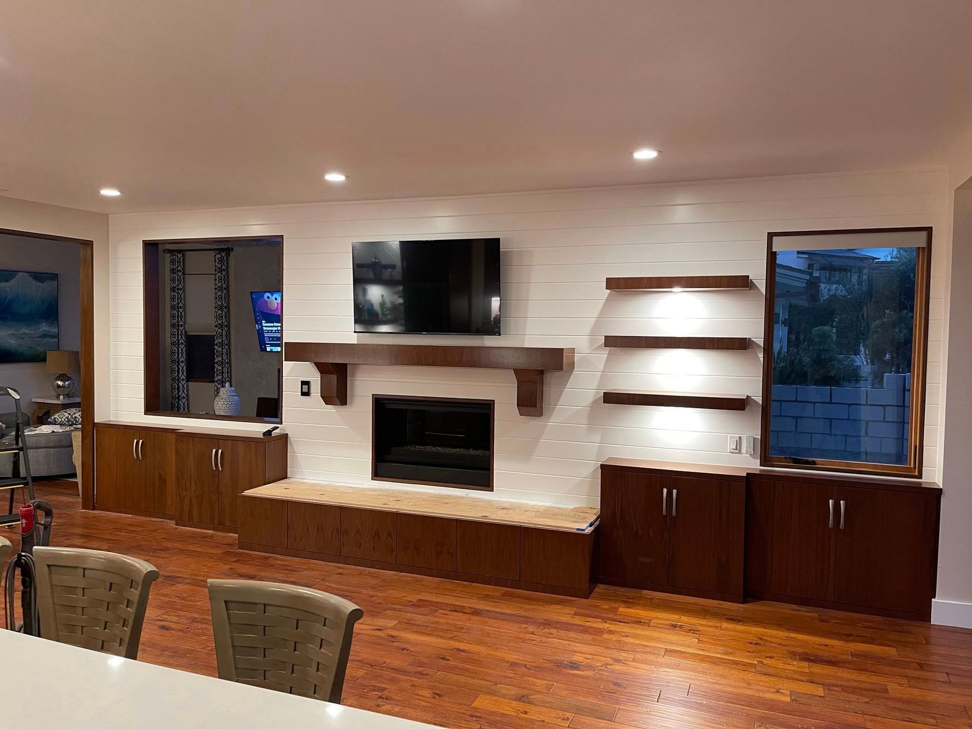 Living room with fireplace, TV, built-in shelving, and dark wood cabinetry.