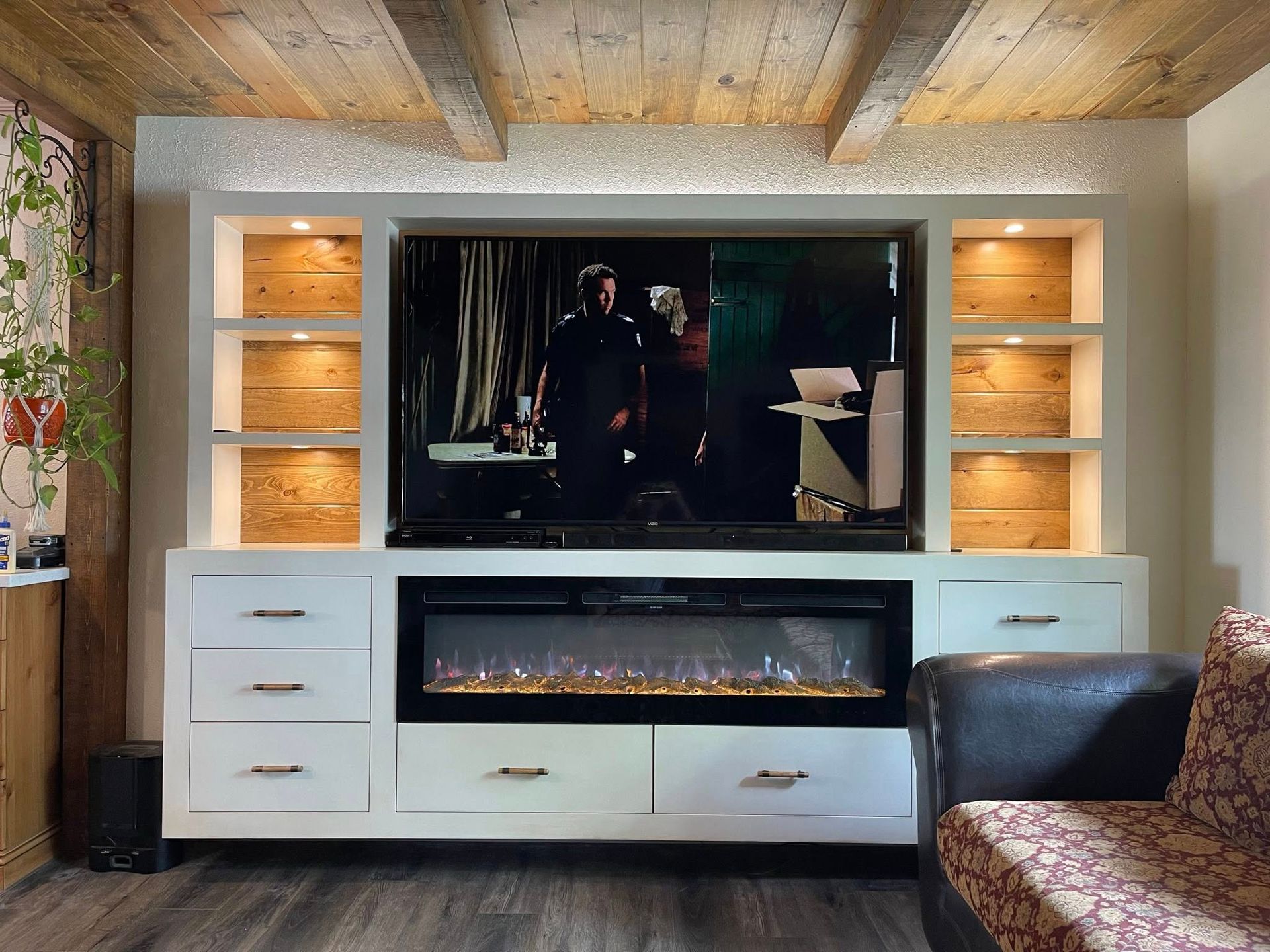 Built-in entertainment center with a TV, fireplace, and shelves with wood paneling.