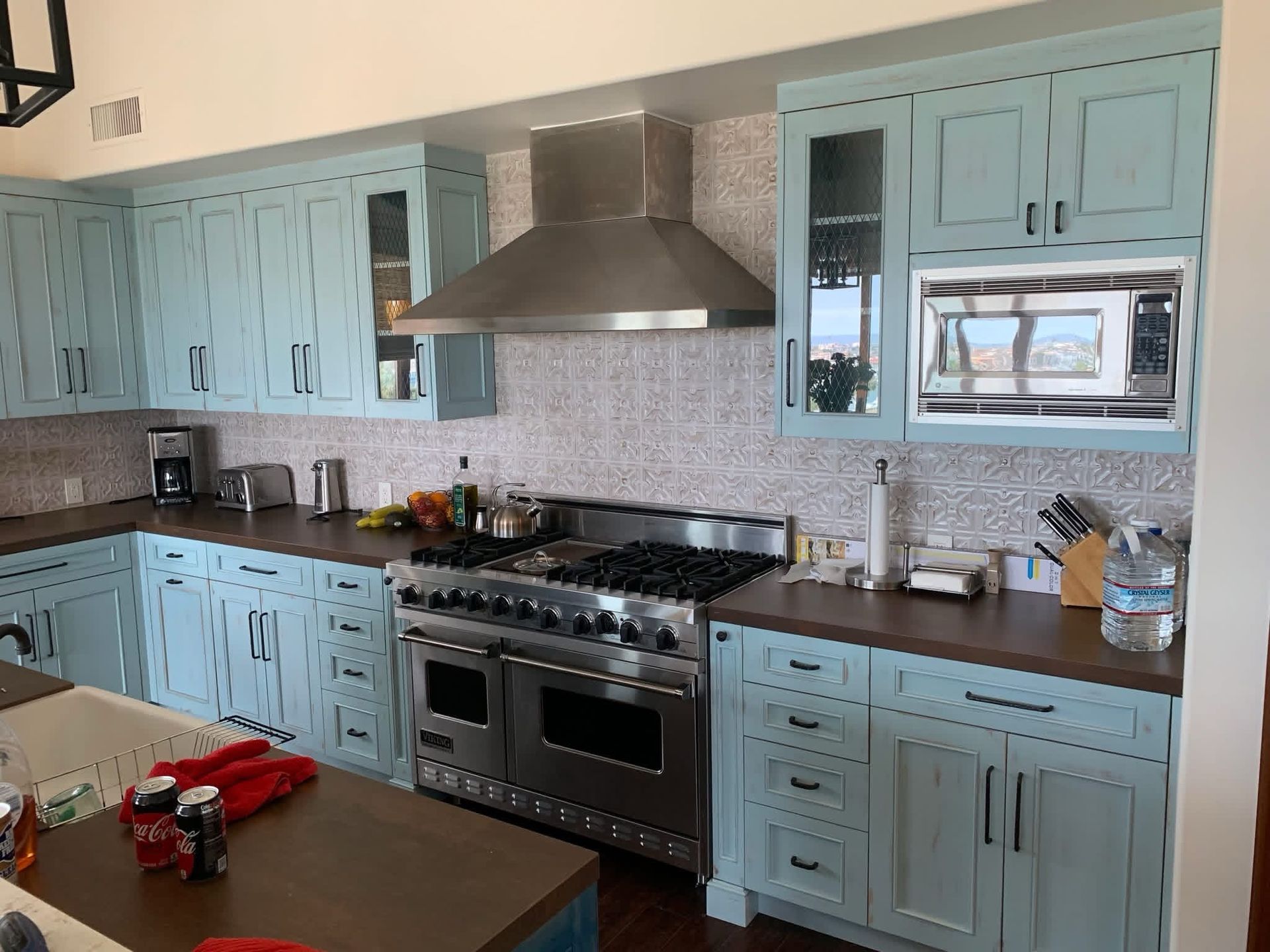 Kitchen with light blue cabinets, stainless steel appliances, and a dark countertop.